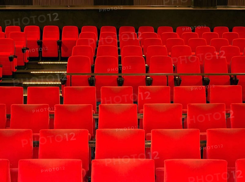 Indoor scenery showing a movie theater with red seats in warm ambiance