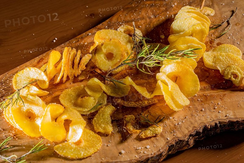 Some deep-fried spiral-sliced potatoes with some thyme on wooden board