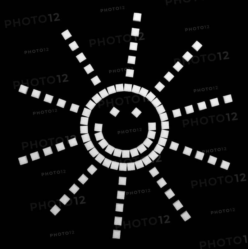Shiny smiling emoji made of lump sugar pieces in black back