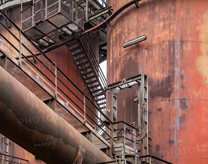 Weathered rundown industrial scenery with old corroded steel girders, stairs and metal tubes
