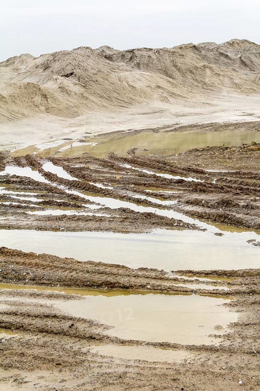 Wet scenery with skidmarks around a light brown heap of earth