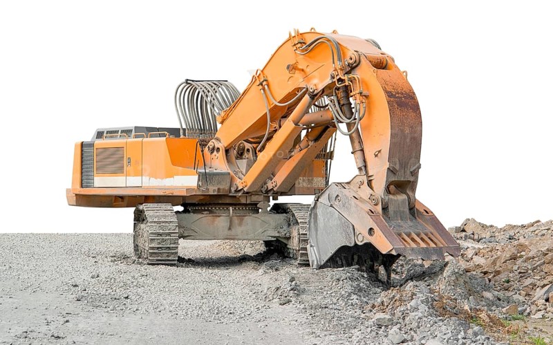 Huge orange colored tracked excavator partly isolated on stony ground