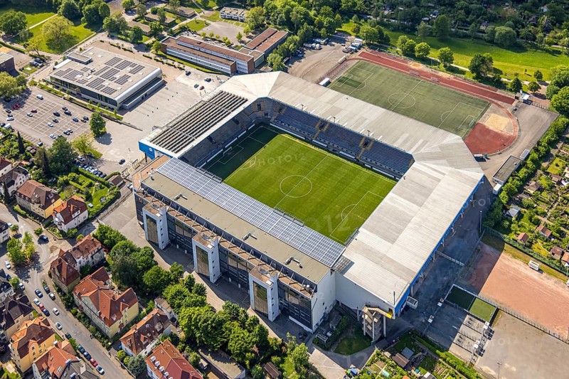 Aerial view, football stadium SchücoArena of DSC Arminia Bielefeld, also Almstadion or Bielefelder Alm, solar roof, centre, Bielefeld, East Westphalia, North Rhine-Westphalia, Germany, football stadium, SchücoArena, DSC Arminia Bielefeld, Almstadion, Bielefelder Alm, sports facility, architecture, leisure, football, sport, top view, city, urban, infrastructure, stadium, green, field, area, open-air, venue, daylight, outdoor, landscape, city view, geography, destination, sight, culture, leisure facility