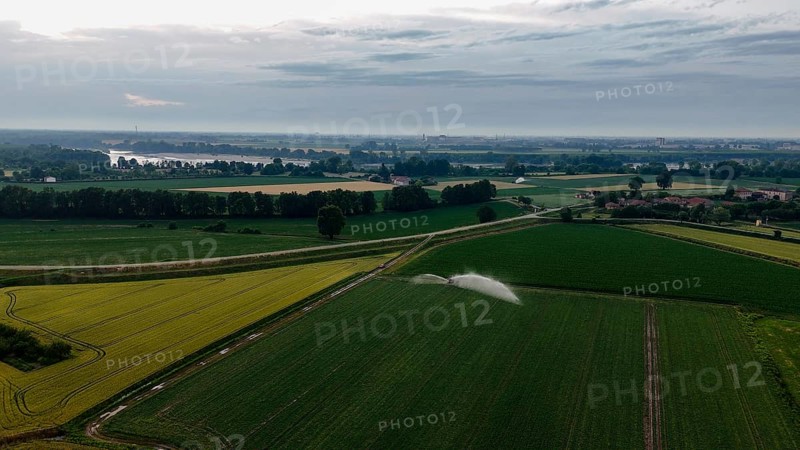 Aerial view of sophisticated sprinkler irrigation systems nurturing lush green soybean crops across expansive agricultural fields during a vibrant springtime in the fertile Po Valley region of Northern Italy showcasing modern farming techniques for efficient water distribution