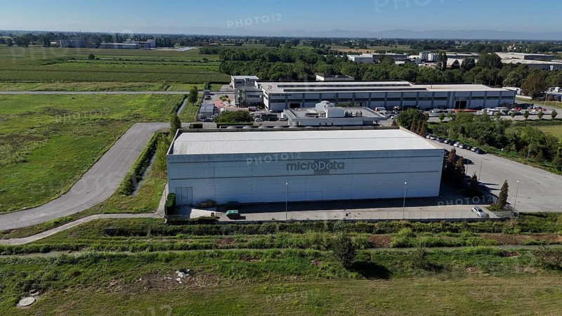 Cremona, Italy August 22nd 2025 Aerial view of the MicroData Group data center building, prominently situated among green fields, supporting cloud storage and data management