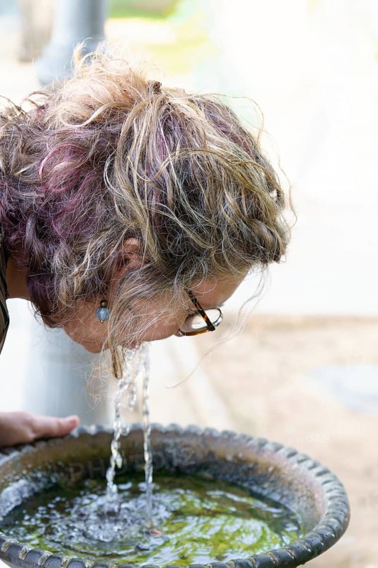 Woman refreshing herself by drinking water directly from a park fountain