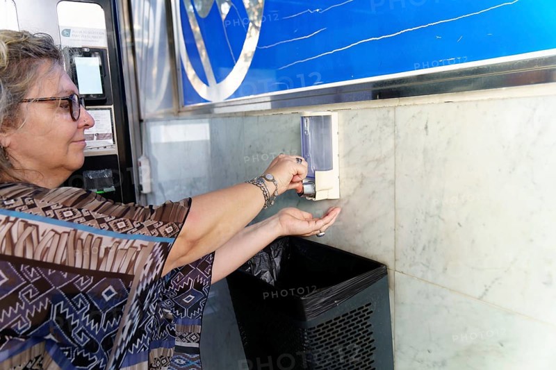 Woman disinfecting hands with antibacterial gel dispenser for coronavirus prevention