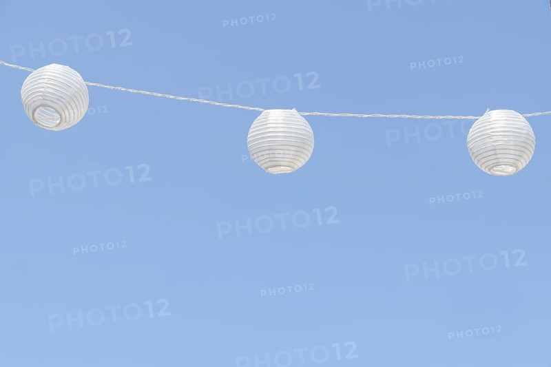 White paper lanterns decorating an outdoor space, adding a festive touch against a clear blue sky