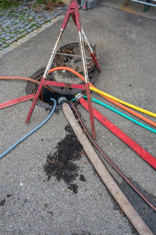 Water hoses and warning triangle on tarmac above open gully, Circus-Krone, Kempten, Allgäu, Bavaria, Germany