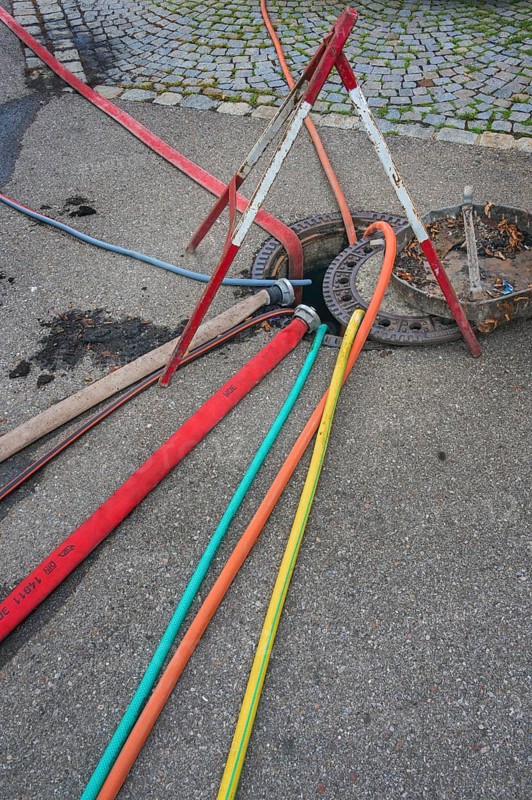 Water hoses and warning triangle on tarmac above open gully, Circus-Krone, Kempten, Allgäu, Bavaria, Germany