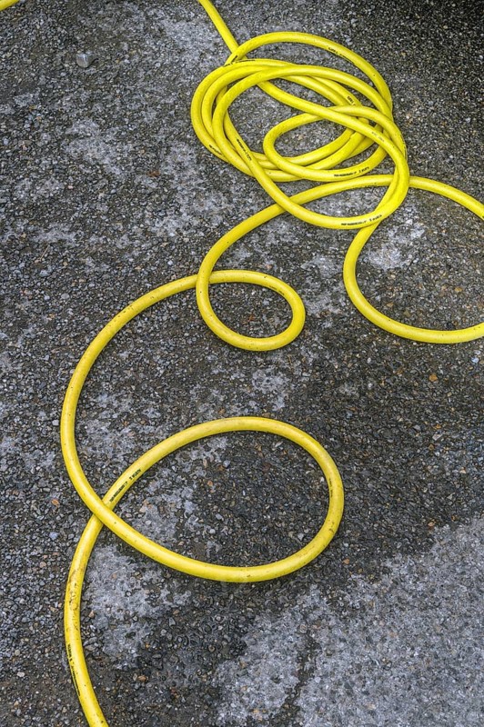 Twisted yellow water hose on asphalt, Allgäu, Bavaria, Germany