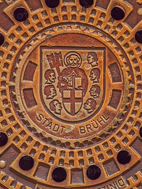 Round manhole cover with city coat of arms, Cologne collegiate cross, St Peter in cloak, key, book, heads of seven aldermen, inscription, Brühl, North Rhine-Westphalia, Germany