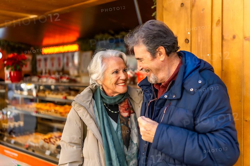 Happy senior couple smiling and enjoying time together during christmas holidays at a winter market