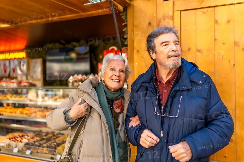 Happy senior couple strolling arm in arm at a traditional christmas market, enjoying the festive atmosphere and holiday cheer