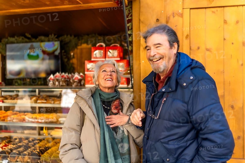 Cheerful senior couple smiling and enjoying the festive atmosphere at a christmas market in a winter city