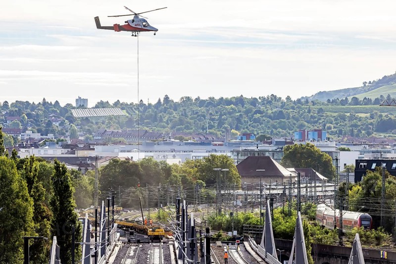 Track construction from the air. At Bad Cannstatt railway station, a transport helicopter transports 26 catenary masts to their destination. The masts, weighing up to 2.4 tonnes, were delivered by rail. The reason for this is to improve the infrastructure as part of the Stuttgart 21 project. Stuttgart, Baden-Württemberg, Germany