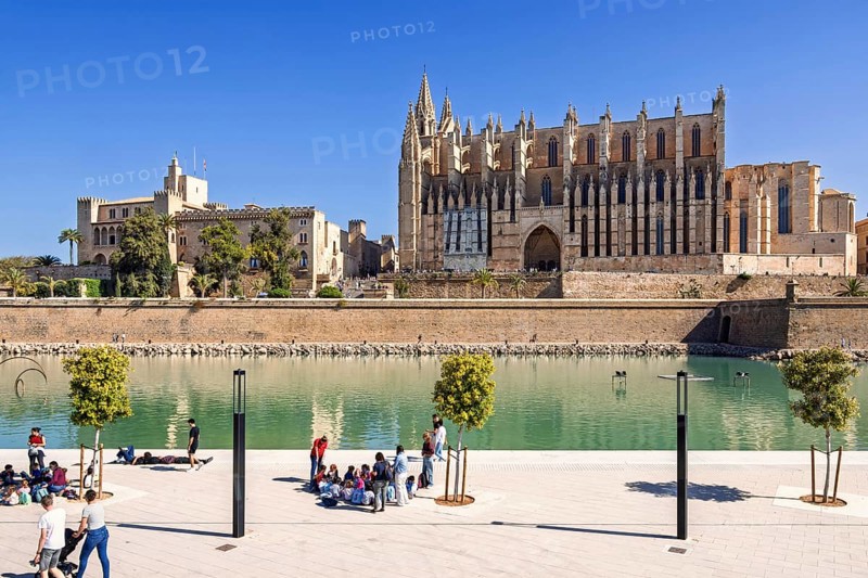 View at Palma cathedral and people by the water pond in the Parque del mar, Palma de Mallorca, Mallorca, Spain