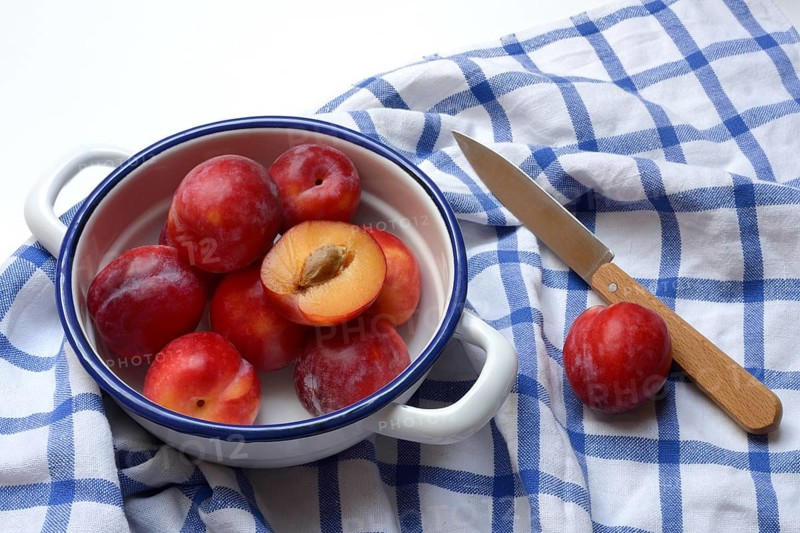 Red plums in skin on cloth, Prunus domestica