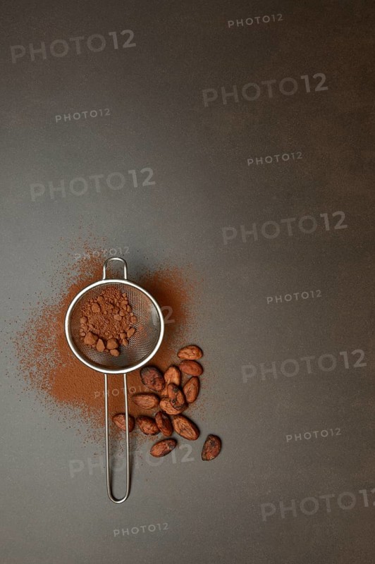 Kitchen sieve with cocoa powder, cocoa and cocoa beans