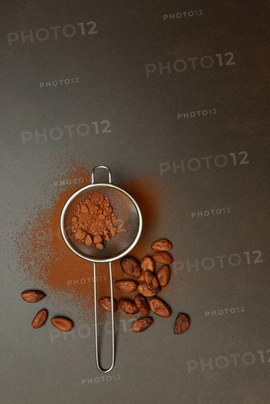 Kitchen sieve with cocoa powder, cocoa and cocoa beans
