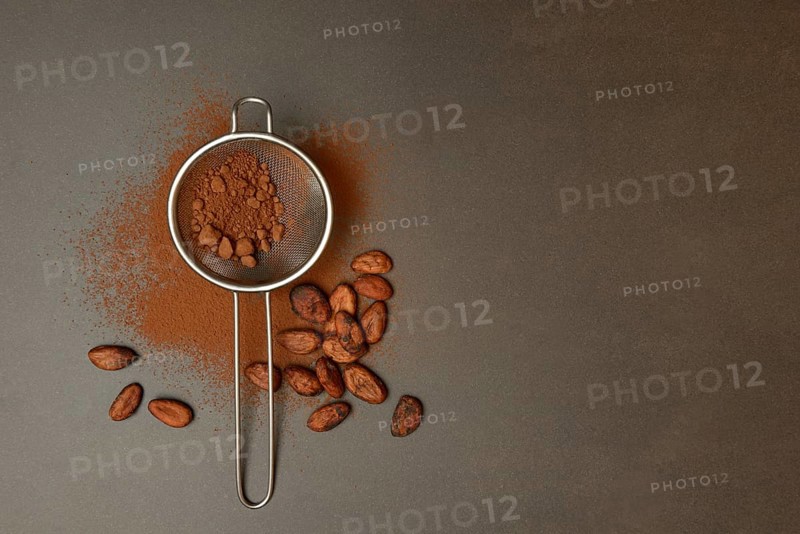 Kitchen sieve with cocoa powder, cocoa and cocoa beans