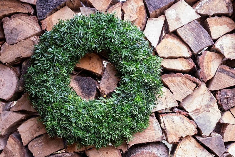 Yew wreath in front of a pile of firewood, North Rhine-Westphalia, Germany