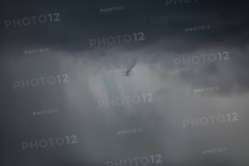 Aircraft breaks through cloud cover and drags a visible wake of vortices behind it