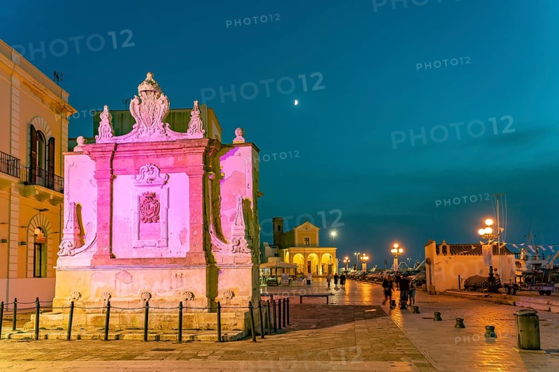 The colourfully illuminated Greek fountain Fontana Greca at dusk, Gallipoli, Apulia, Italy