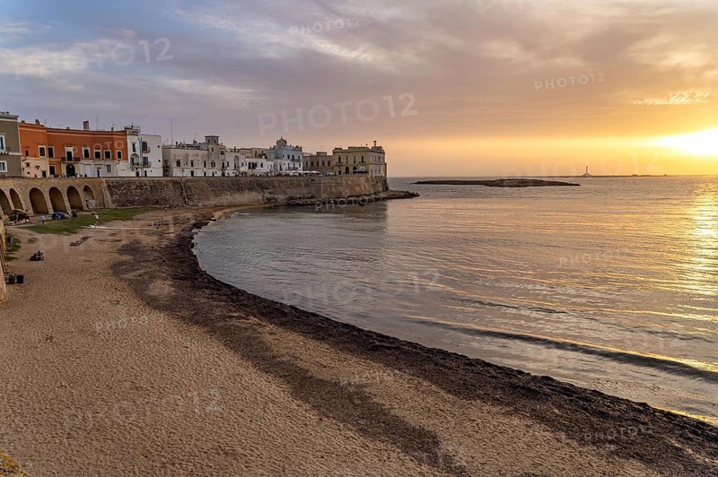 The town beach Spiaggia della Purità and the old town centre at sunset, Gallipoli, Apulia, Italy