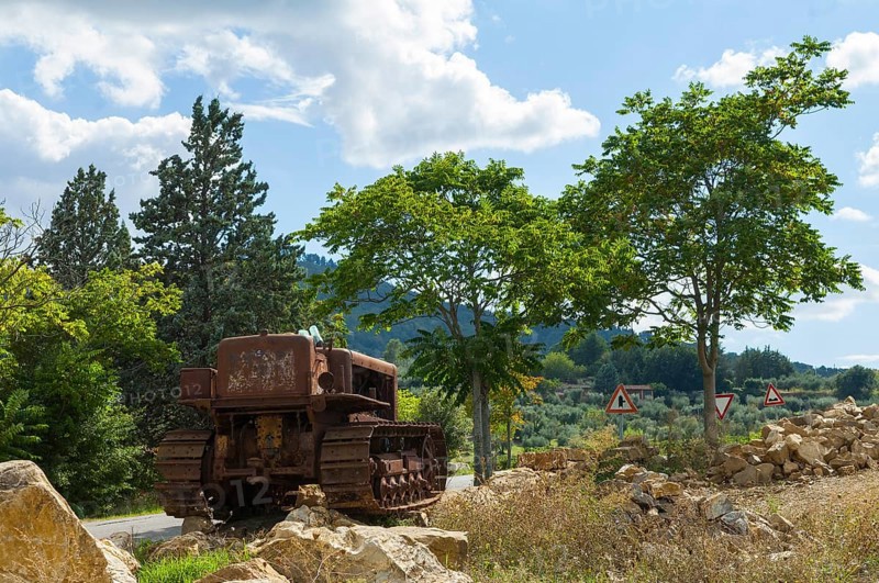 Old, heavily rusted bulldozer for road construction stands abandoned on rocks, industrial relic
