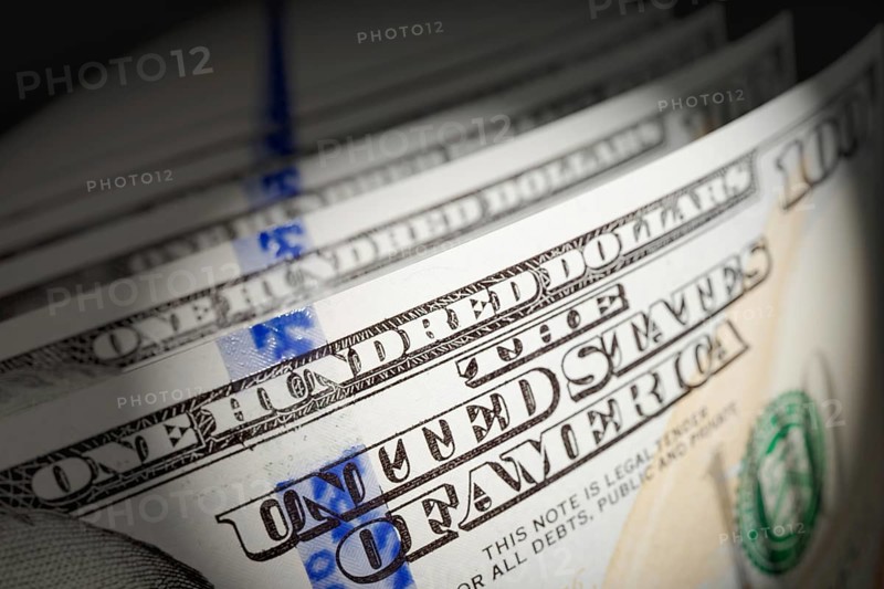 Spot lit abstract close-up angle of U.S. 100 dollar bills isolated on a black background