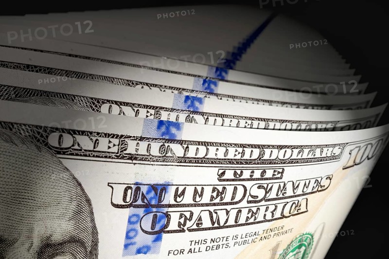 Spot lit abstract close-up angle of U.S. 100 dollar bills isolated on a black background
