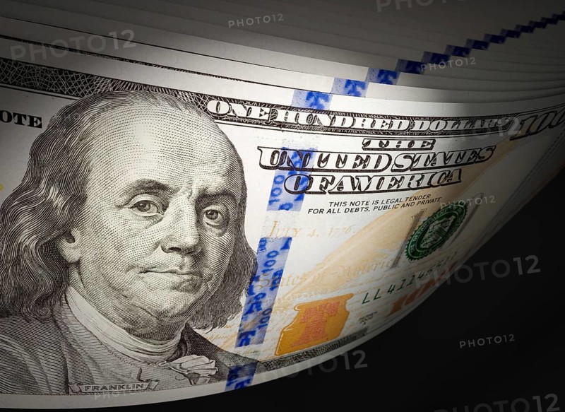 Spot lit abstract close-up angle of U.S. 100 dollar bills isolated on a black background
