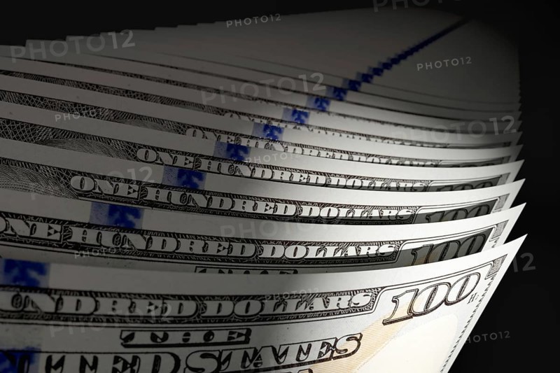 Spot lit abstract close-up angle of U.S. 100 dollar bills isolated on a black background