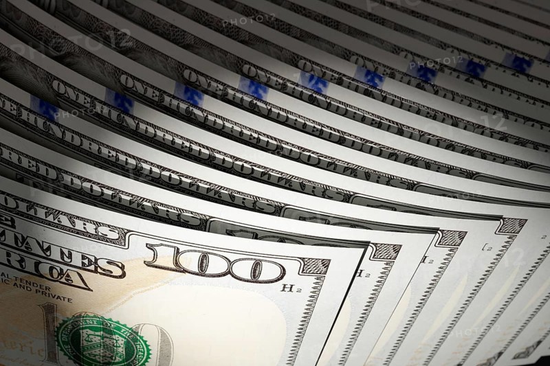 Spot lit abstract close-up angle of U.S. 100 dollar bills isolated on a black background