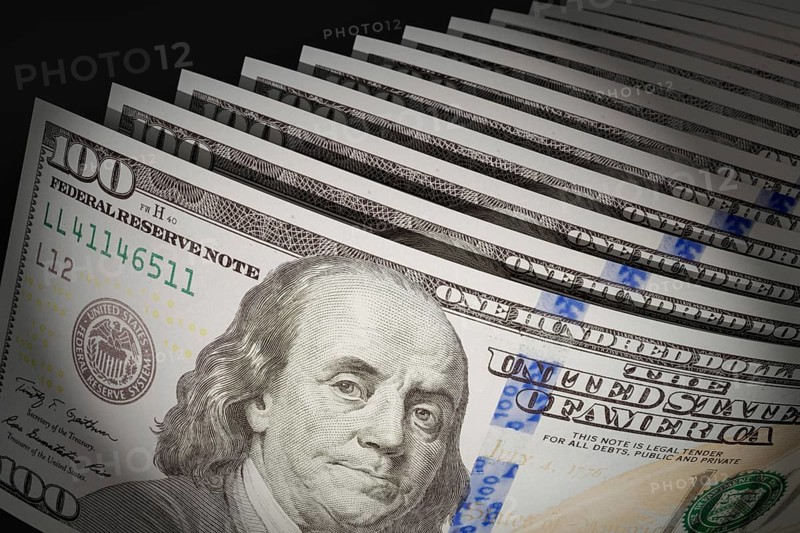 Spot lit abstract close-up angle of U.S. 100 dollar bills isolated on a black background