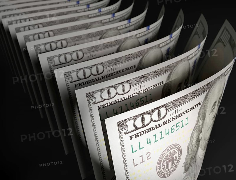 Spot lit abstract close-up angle of U.S. 100 dollar bills isolated on a black background