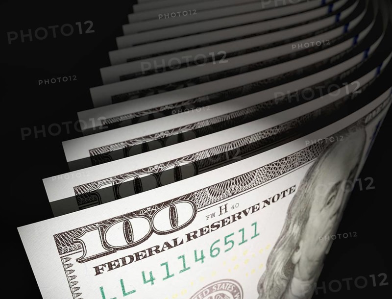 Spot lit abstract close-up angle of U.S. 100 dollar bills isolated on a black background