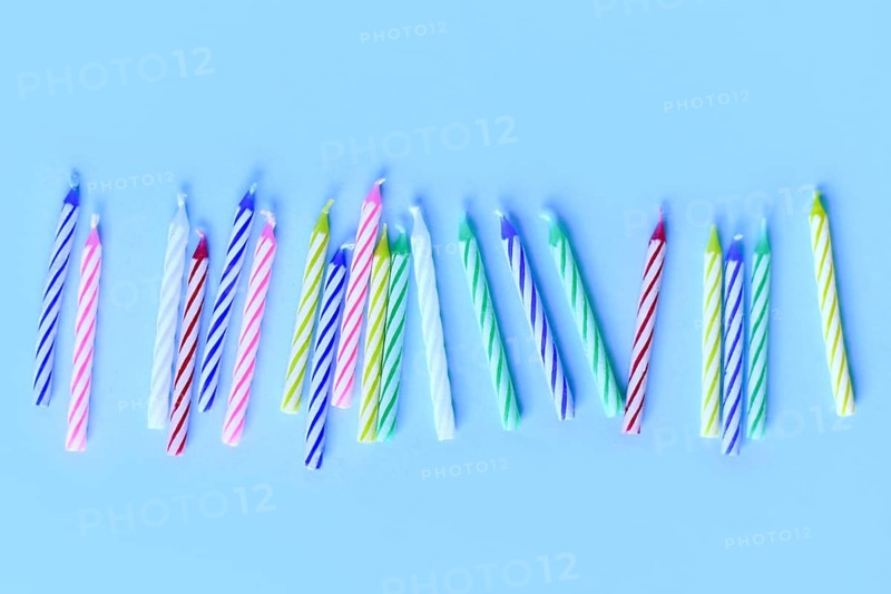 Row of colorful birthday candles on blue background