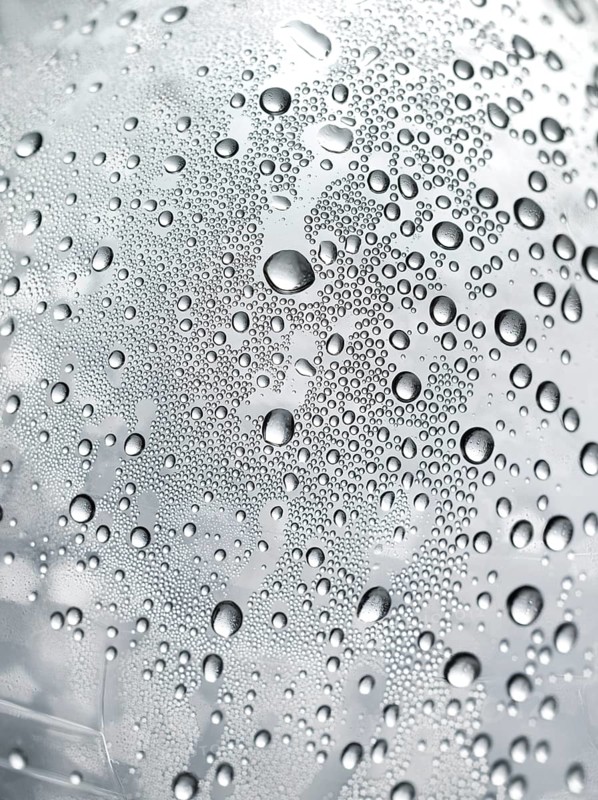 Drops of water on plastic bottle, neutrally illuminated, detailed view