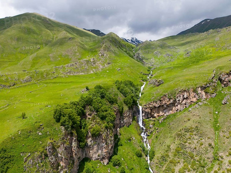 Landscape with long waterfall between green mountains under a cloudy sky, aerial view, Toti Waterfall or Arsha Waterfall, Arshistskhali River, Kazbegi, Qasbegi, Stepantsminda, Georgian Military Road, Mtskheta-Mtianeti Province, High Caucasus, Georgia