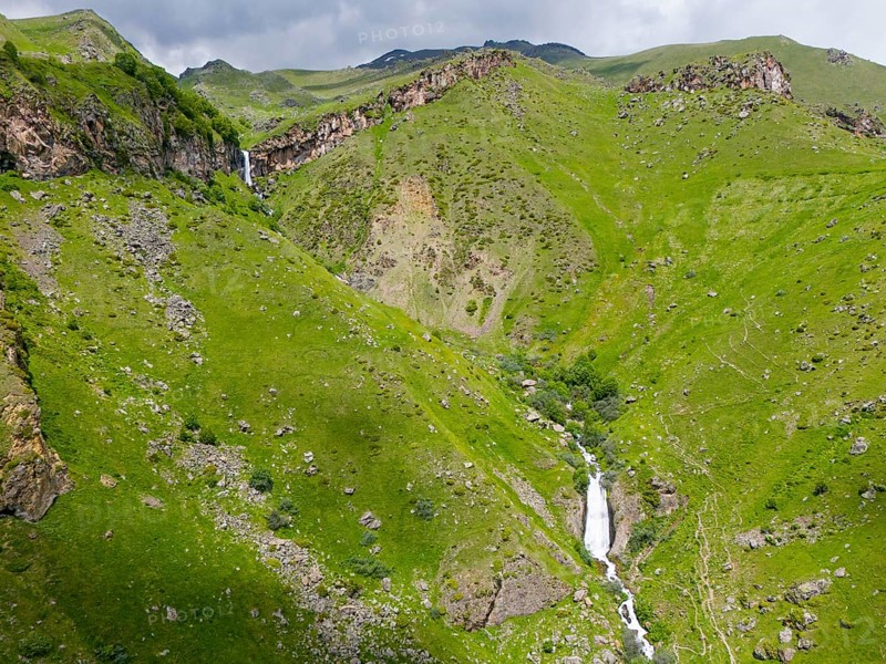 Waterfall in a green valley between rocky mountains, aerial view, Toti waterfall or Arsha waterfall, twin cascades, Arshistskhali river, Kazbegi, Qasbegi, Stepantsminda, Georgian Military Road, Mtskheta-Mtianeti province, High Caucasus, Georgia