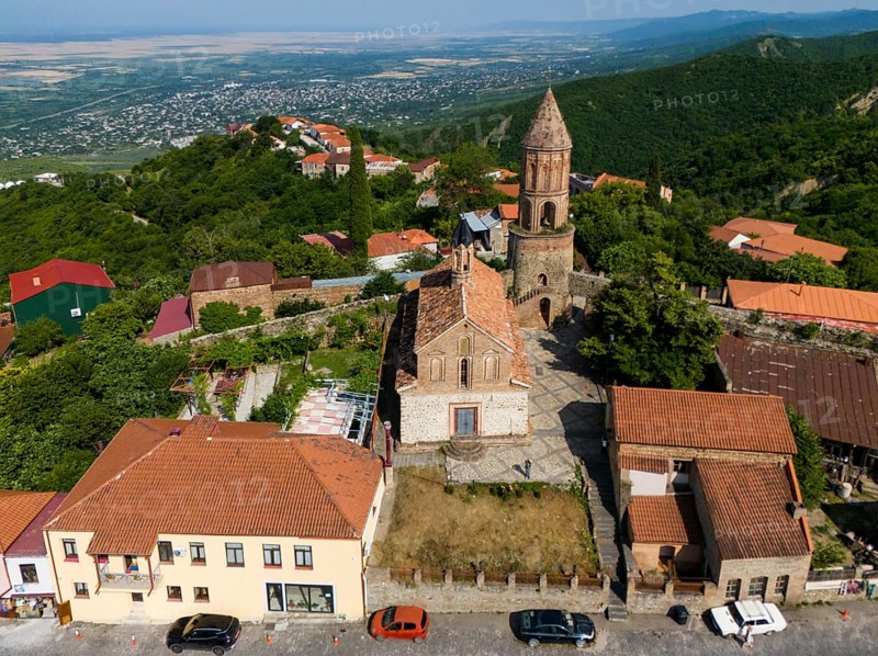 Village view with church tower and brick buildings, surrounded by green hills and wide landscape, aerial view, Church of St George, St George, Sighnaghi, Signagi, Kakheti Province, Greater Caucasus, Georgia, Near East