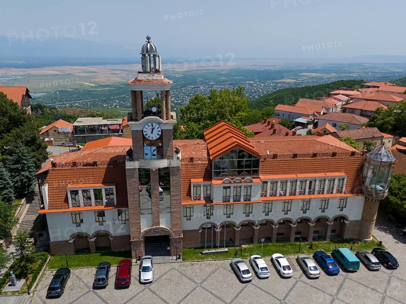 Large building with clock tower and surrounding traditional roofs on a slope, aerial view, town hall, Sighnaghi, Signagi, Kakheti Province, Greater Caucasus, Georgia, Near East