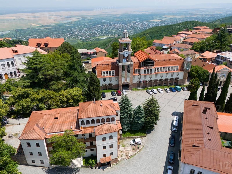 Square with a dominant tower and traditional buildings surrounded by green hills, aerial view, Sighnaghi, Signagi, Kakheti Province, Greater Caucasus, Georgia, Near East