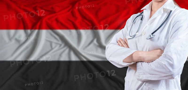 Doctor with crossed arms on Yemen flag. Yemeni health and care concept. Female doctor on Yemen flag