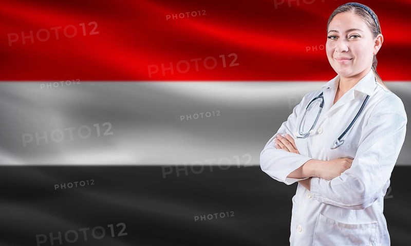 Female doctor on Yemen flag. Doctor with crossed arms on Yemen flag. Yemeni health and care concept