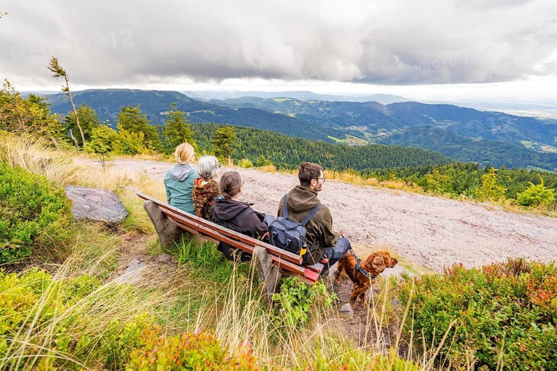 Group on a bench marvelling at the panorama over the mountain landscape with clouds in the sky, Mummelsee, Seebach, Ortenau district, Black Forest, Germany