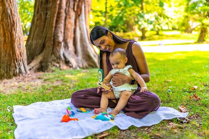 Latin mother and her baby daughter enjoying playtime with colorful toys on a blanket, creating a heartwarming scene of family bonding in a park