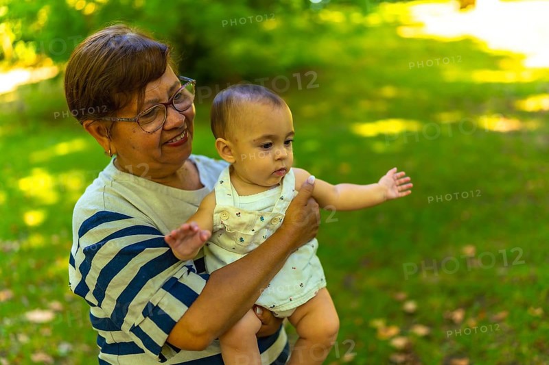 Smiling grandmother cradling her adorable granddaughter in a vibrant green park, enjoying a sunny day filled with joy and connection